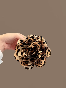Detailed close-up of a layered leopard print fabric flower hair clip accessory