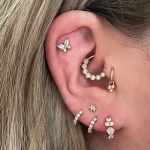 Macro shot of gold S925 silver butterfly earrings with pearls and zircon on ear cartilage