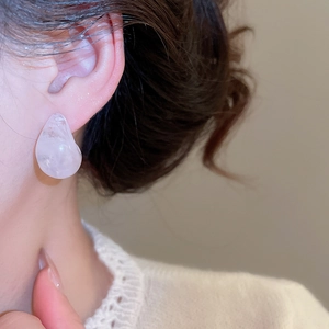 Close-up of pink resin waterdrop earrings worn by model with minimalist fashion style