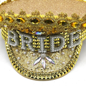 Close-up of golden wedding captain hat with sequins, pearls, and BRIDE lettering decoration