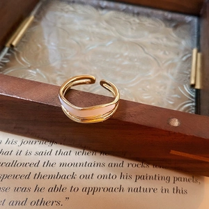 Elegant gold wavy double-layer open ring with white enamel finish on vintage wood