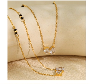 Detail of gold necklace featuring two sparkling rhinestones and black beads on a thin chain