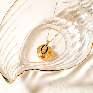 Golden Virgin Mary pendant necklace with orange crystal and black enamel detail