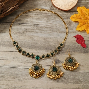 Luxury gold vintage pearl and zircon jewelry set with green gemstones and tassels on wood