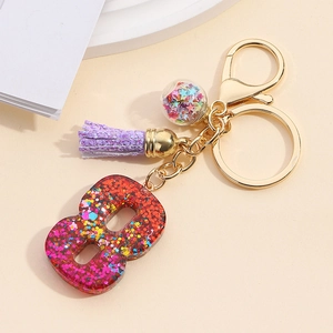 Close-up of number 8 keychain with red glitter resin, purple tassel and golden ring