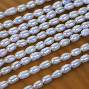 Strands of 4mm high luster white rice shaped natural freshwater pearls on wood