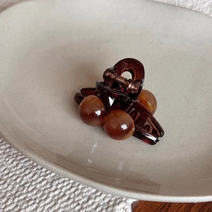 Detail of amber cherry hair claw clip with beads resting on a ceramic display dish