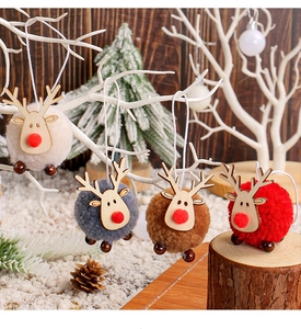 Close-up of plush reindeer pom-pom ornaments in four colors on a white branch