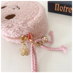 Detailed macro of pink plush bag fabric with golden flower zipper and beaded cord puller