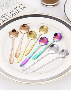 Macro detail of eight stainless steel flower shaped dessert spoons in varied metallic finishes