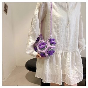 Detail of handmade purple crochet puff flower bag with pearl clasp and woven strap