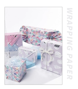 Scatole regalo confezionate con carta a tema marino con squame di sirena e conchiglie