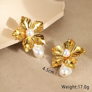 Macro shot of gold floral earrings featuring brushed metal and baroque pearl details