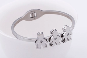 Detail of silver bangle featuring three small human-shaped charms with tiny zircon stones