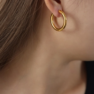 Polished gold plated titanium steel hoop earrings featuring a minimalist tubular design