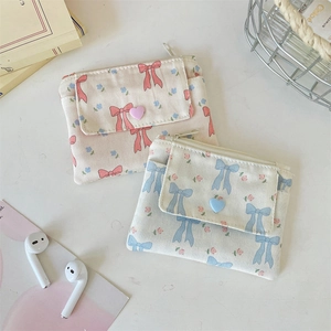 Detailed macro view of floral canvas wallets with bow patterns and heart button closure