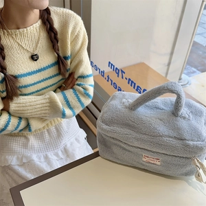 Detail of the light blue plush makeup bag showing soft sherpa texture and top handle