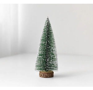 Close-up of mini snow-tipped Christmas tree with a natural wooden base for desktop decor