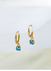 Detailed close-up of gold titanium steel earrings with a round blue zircon pendant