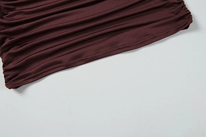 Gros plan sur la texture froncée et les coutures fines d'une robe moulante rouge-brun