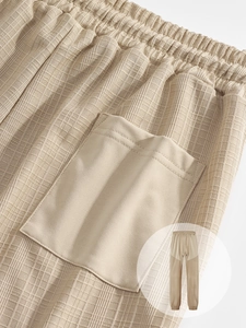 Detail shot of khaki waffle textured jogger pants with elastic drawstring waist and pocket