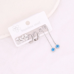Parure de boucles d'oreilles trèfle et œil maléfique en acier inoxydable argenté sur fond blanc