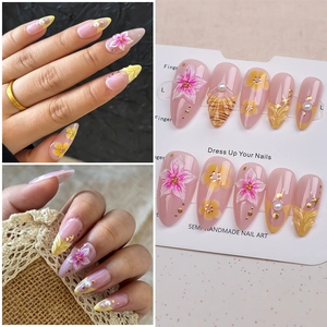 Detail of 3D sakura flowers and gold foil accents on almond press-on nails