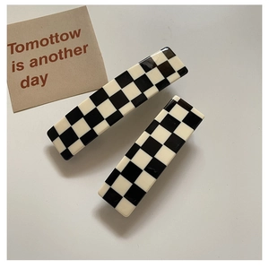 Close-up of black and white checkered acetate hair claw clips in a two-piece set