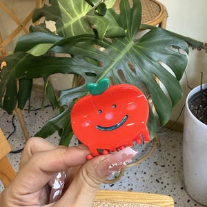 Cute red apple hair claw clip with smiley face and green leaf detail in hand