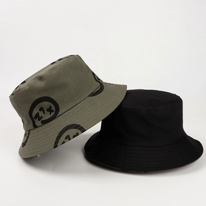 Detail of army green bucket hat with graffiti smiley face and classic black cotton hat