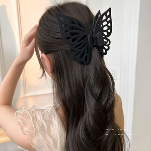 Macro detail of large black matte butterfly hair claw clip worn on a model's hair