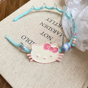 Detail of blue fabric headband with cartoon kitty mascot and decorative beads