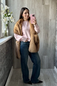 Detail of a fluffy faux fox fur shawl in brown paired with a pink sweater and jeans