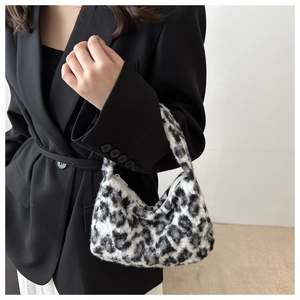 Close-up of leopard print plush crescent bag held by a model in a black suit blazer