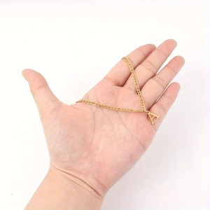Minimalist gold stainless steel necklace with letter A pendant held by a hand on white