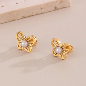 Close-up of golden hollow butterfly stud earrings with pearl centers in high detail
