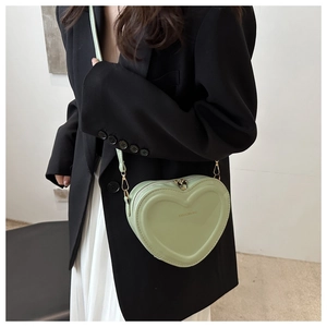 Detail view of heart-shaped light green patent leather bag with gold fashion lettering