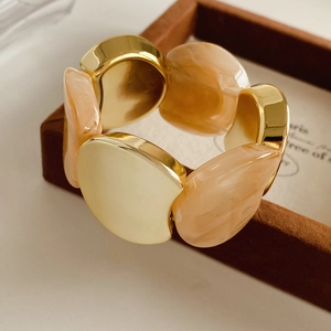 Close-up of gold metal modules and marble-textured pink resin on the elastic bracelet