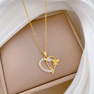 Detail of gold heart and butterfly pendant with sparkling cubic zirconia on silk