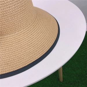 Gros plan d'un chapeau de paille tressé avec bordure noire sur un fond de pelouse