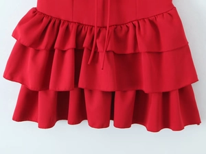 Detail of red tiered ruffle hem with layered pleated fabric on a solid dress