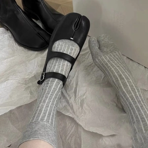 Detail of grey striped split-toe socks worn with black Mary Jane Tabi style shoes