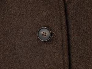 Detail of dark brown wool blend fabric and a black resin button on the coat