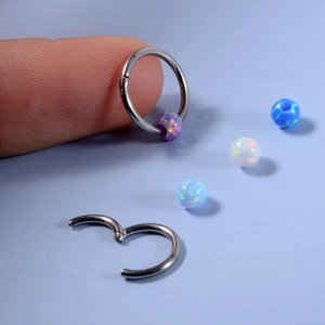 Close-up of stainless steel clicker rings with colorful opal stones in a blue background