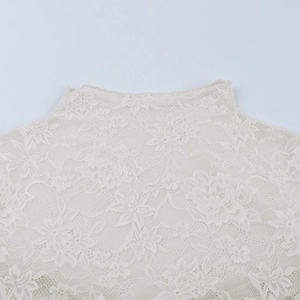 Gros plan détaillé sur la texture de dentelle florale beige et les détails du col