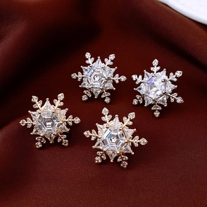 Macro shot of hexagonal snowflake earrings with cubic zirconia on red silk fabric