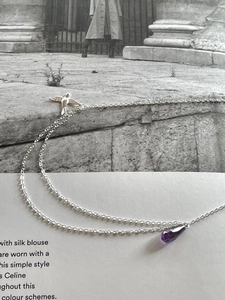 Macro shot of a 925 sterling silver swallow necklace with a purple teardrop pendant