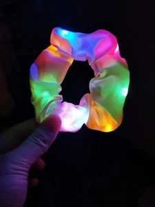 Macro detail of LED glowing scrunchie with colorful lights and satin texture