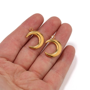 Pair of polished gold crescent moon pendants held in hand for DIY necklace making