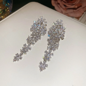 Detail of floral tassel earrings with sparkling zircons on white leather jewelry box